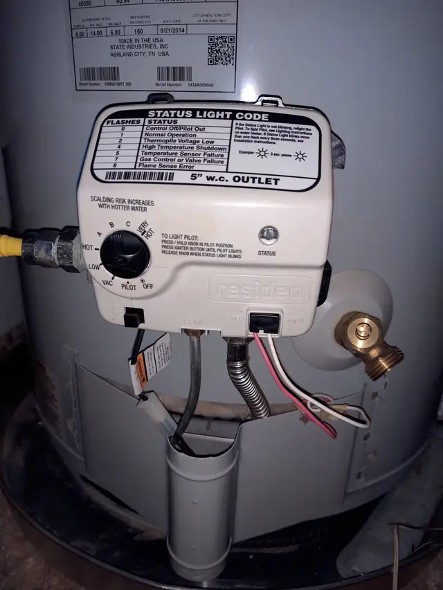 Close-up of a gas water heater control valve and its status light label